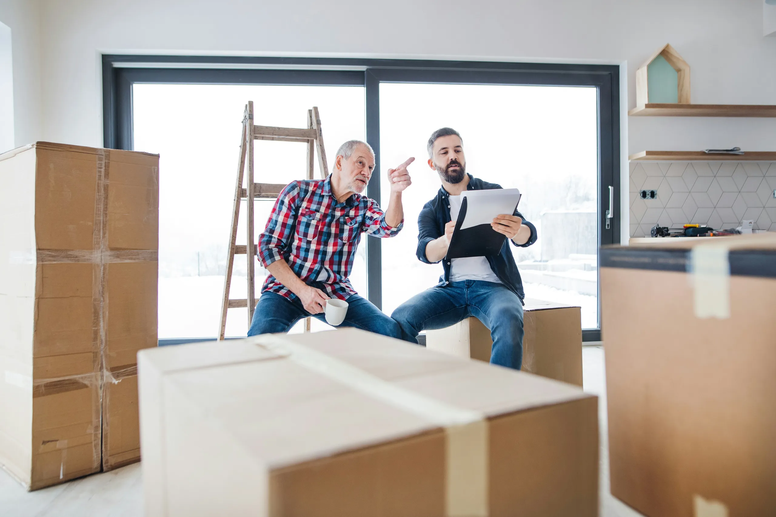 Dos hombres planificando una mudanza entre cajas en la cocina